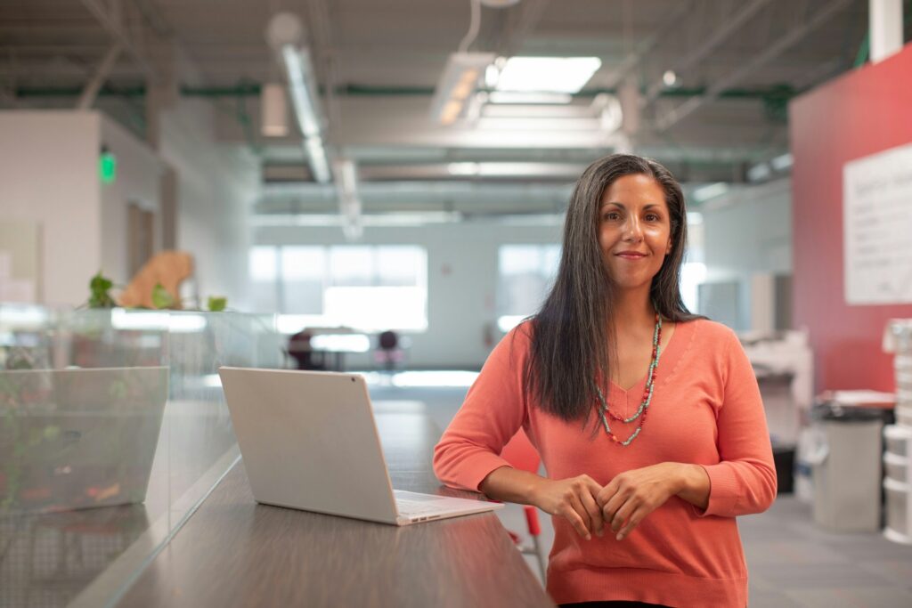 Vagas Híbridas em Plataforma de Seguros woman in orange long sleeve shirt sitting beside table with macbook pro